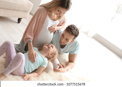 Young Pregnant Woman With Her Family At Home