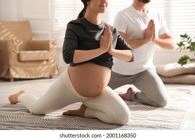 Young pregnant woman with her husband practicing yoga at home, closeup - Powered by Shutterstock