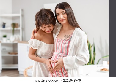 Young pregnant woman with her wife hugging in kitchen - Powered by Shutterstock