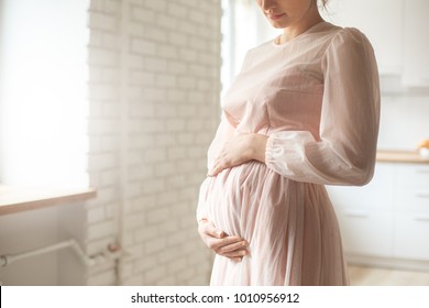 Young Pregnant Woman At Home Maternity Concept Wearing Dress Touching Belly Tenderness