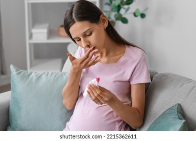 Young Pregnant Woman With Nosebleed And Tissue At Home