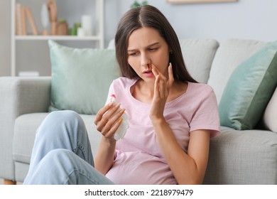 Young Pregnant Woman With Nosebleed And Tissue At Home