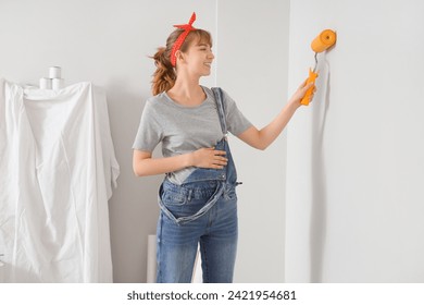 Young pregnant woman painting wall during repair in children's room - Powered by Shutterstock