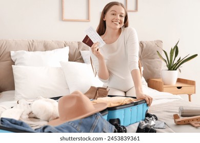 Young pregnant woman with passport packing suitcase for vacation in bedroom - Powered by Shutterstock