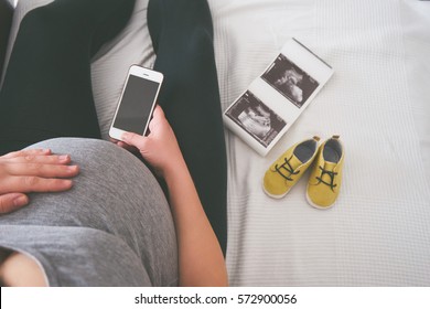 Young pregnant woman relaxing on sofa with smart phone