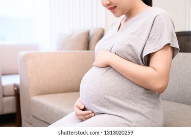 Young pregnant woman sitting on sofa and holds her belly during to see a doctor for check up at hospital - Shutterstock ID 1313020259