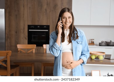Young pregnant woman talking by mobile phone in kitchen - Powered by Shutterstock