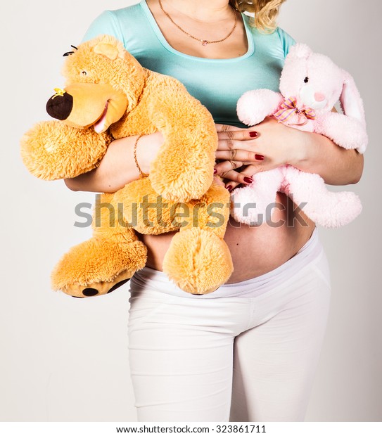 Young pregnant\
woman with  toy on her\
belly