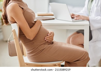 Young pregnant woman visiting her gynecologist in clinic, she sitting on chair and talking to her doctor - Powered by Shutterstock