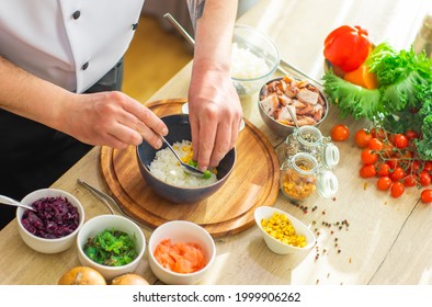 Young prepares a poke bowl in a modern kitchen. The man prepares food at home. Cooking healthy and tasty food.