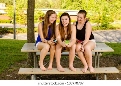 Young pre-teen girls texting while hanging out in front of their school