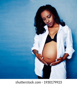young pretty african american woman pregnant happy smiling, posing on blue background, lifestyle people concept copyspace
