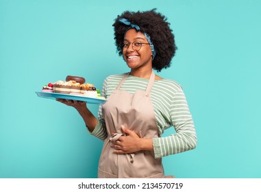 young pretty afro woman baker with cakes - Shutterstock ID 2134570719