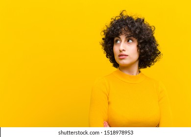 Young Pretty Afro Woman Feeling Happy, Proud And Hopeful, Wondering Or Thinking, Looking Up To Copy Space With Crossed Arms