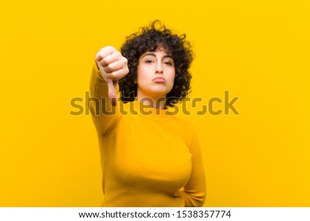 young pretty afro woman feeling cross, angry, annoyed, disappointed or displeased, showing thumbs down with a serious look