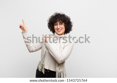 young pretty afro woman feeling joyful and surprised, smiling with a shocked expression and pointing to the side