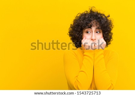 young pretty afro woman looking worried, anxious, stressed and afraid, biting fingernails and looking to lateral copy space