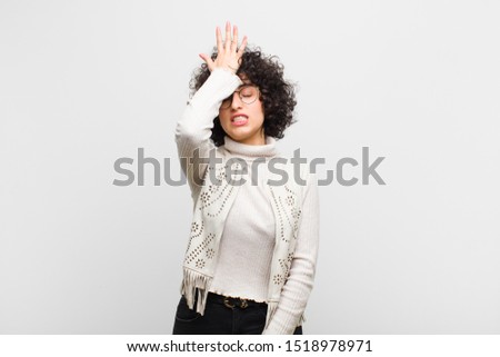 young pretty afro woman raising palm to forehead thinking oops, after making a stupid mistake or remembering, feeling dumb