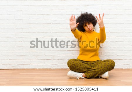 young pretty afro woman smiling and looking friendly, showing number eight or eighth with hand forward, counting down sitting on the floor