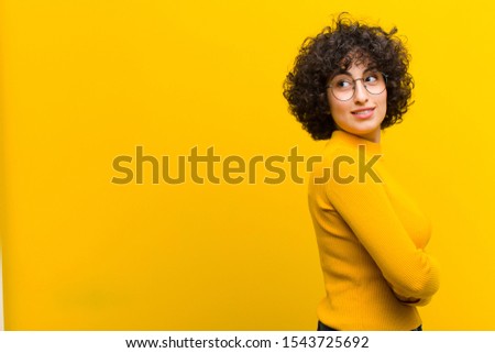 young pretty afro woman smiling gleefully, feeling happy, satisfied and relaxed, with crossed arms and looking to the side