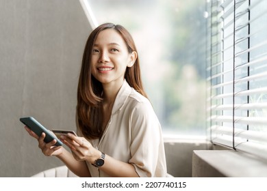 Young pretty asian female using credit card to do online product shopping on her mobile, cashless concept. - Shutterstock ID 2207740115
