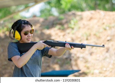 Young pretty asian girl and 22 rifle gun at shooting sports with smiling.