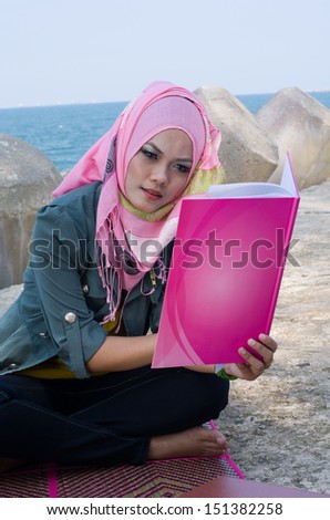 Young pretty Asian Muslim Student in head scarf reading book