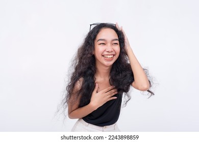A young and pretty asian woman chuckles from a joke. A happy and lighthearted scene. Isolated on a white backdrop. - Shutterstock ID 2243898859