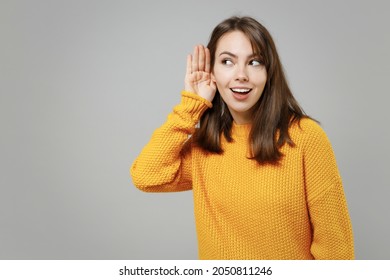Young pretty attractive smart smiling curious caucasian woman 20s wearing casual knitted yellow sweater try to hear you overhear listening intently isolated on grey color background studio portrait - Shutterstock ID 2050811246