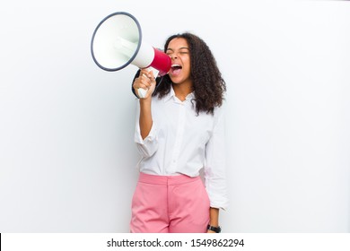 Young Pretty Black Woman With A Megaphone Against White Wall