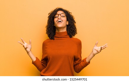 Young Pretty Black Woman Performing Opera Or Singing At A Concert Or Show, Feeling Romantic, Artistic And Passionate Against Orange Wall