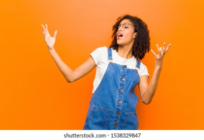 Young Pretty Black Woman Performing Opera Or Singing At A Concert Or Show, Feeling Romantic, Artistic And Passionate Against Orange Wall