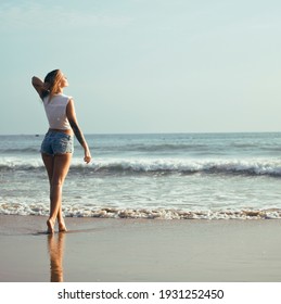 young pretty blond woman at seacoast walking relaxing, fashion lady at sunset, people on summer vacation concept
