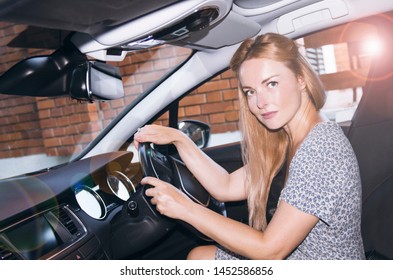 Young Pretty Blonde Woman Driving Car From Parking Garage. Driving Licence Test. Right Side For Driving Vehicle