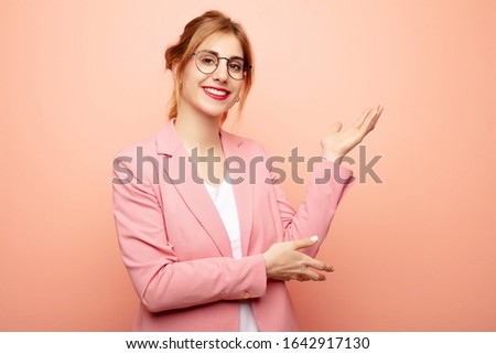 young pretty blonde woman smiling proudly and confidently, feeling happy and satisfied and showing a concept on copy space. business concept
