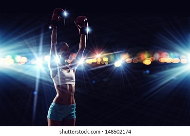 Young pretty boxer woman standing in light flashes