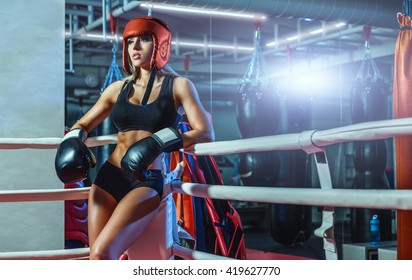 Young pretty boxer woman standing on ring and resting