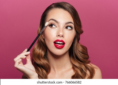 Young Pretty Brunette Lady Making Make Up With Brush For Eyes Isolated Over Pink