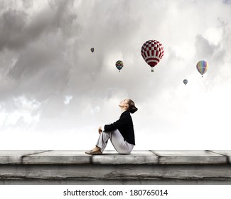 Young Pretty Businesswoman Sitting On Top Of Building With Colorful Balloons Flying Above