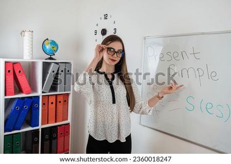 Young pretty caucasian woman explaining language grammar rules standing near blackboard. Learning concept