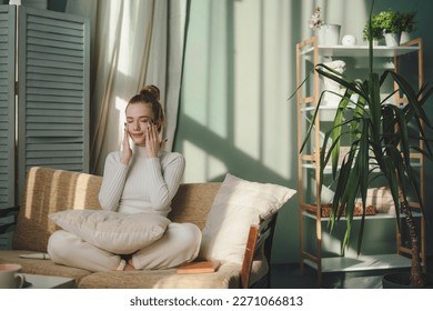 Young pretty caucasian woman sitting on sofa in the morning at home while applying moisturizing face cream, getting ready for work. Beauty and skincare concept - Powered by Shutterstock