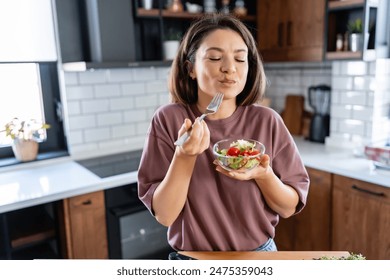 A young pretty cheerful woman is eating a salad. Healthy eating