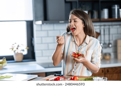 A young pretty cheerful woman is eating a salad. Healthy eating - Powered by Shutterstock