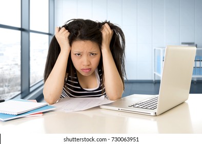 young pretty chinese asian student or business woman tired working and studying on computer laptop looking frustrated and bored at modern office workplace