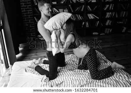 young pretty couple having fun on bed in morning, smiling happy, family living together, bedroom, pajamas, man and woman, laughing, positive emotion, fighting pillows