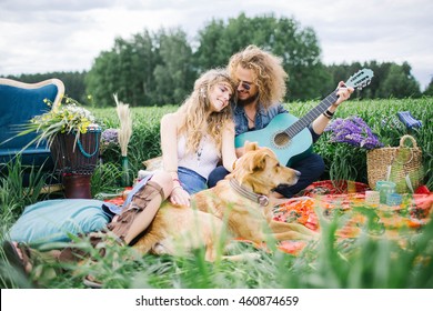Young pretty curly hippie couple with guitar and dog outdoor