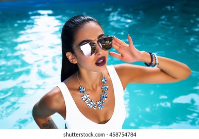 Young pretty fashion sport woman posing outdoor in summer on tropic island in hot weather in bikini on pool party.fashion photo of beautiful tanned woman in elegant black bikini relaxing beside  pool

