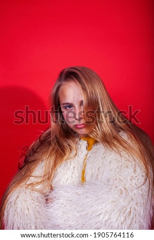 young pretty fashion teenage girl on bright red background, happy smiling lifestyle people concept