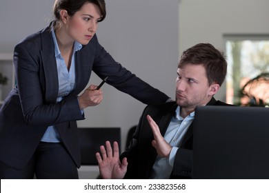 Young pretty female boss threatening to her young handsome employee