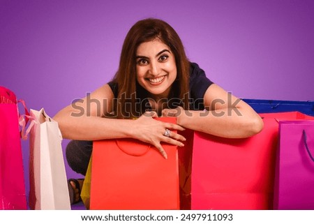 Young pretty female doing shopping with lots of colorful bags on isolated purple background